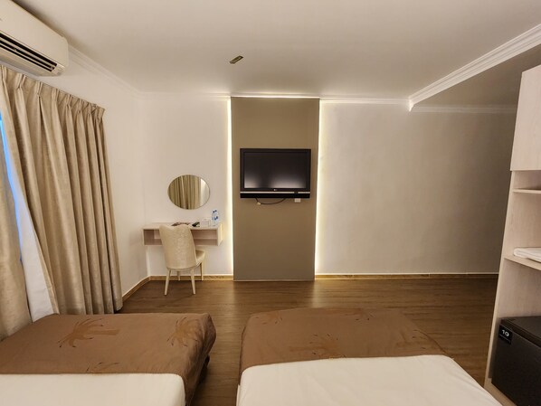 A hotel room with two beds, a desk with a chair, a television, and a wardrobe.