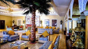 Un vestíbulo espacioso con sofás estampados, una palmera y un gran jarrón decorativo.