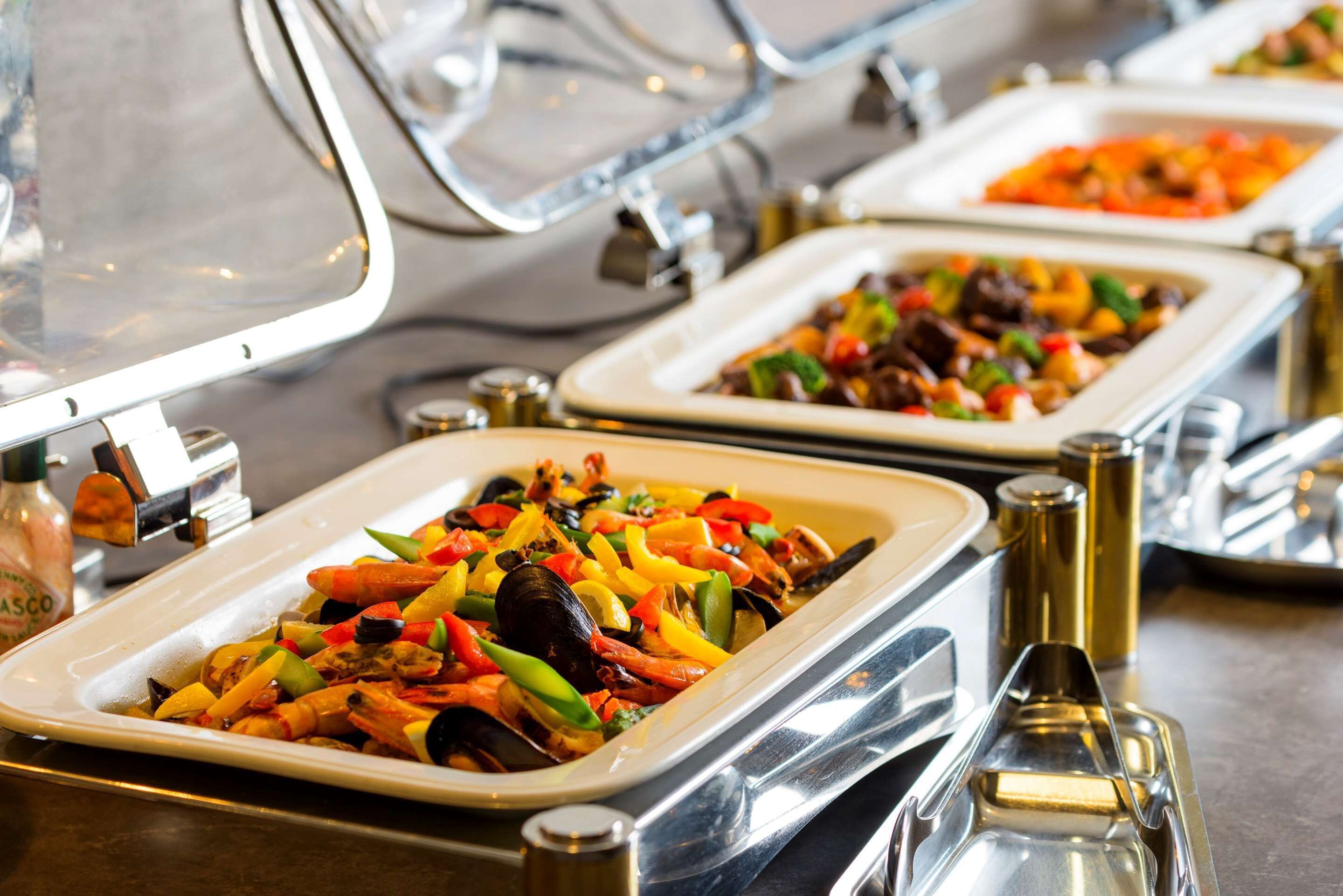 A buffet with seafood dishes, including shrimp and mussels, and various vegetables.