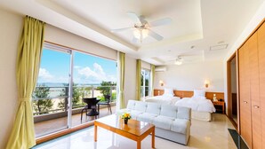 Habitación de hotel con balcón, cama, sofá, mesa de centro y ventilador de techo.