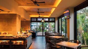 Un restaurante con barra libre, mobiliario de mimbre y vistas al exterior.