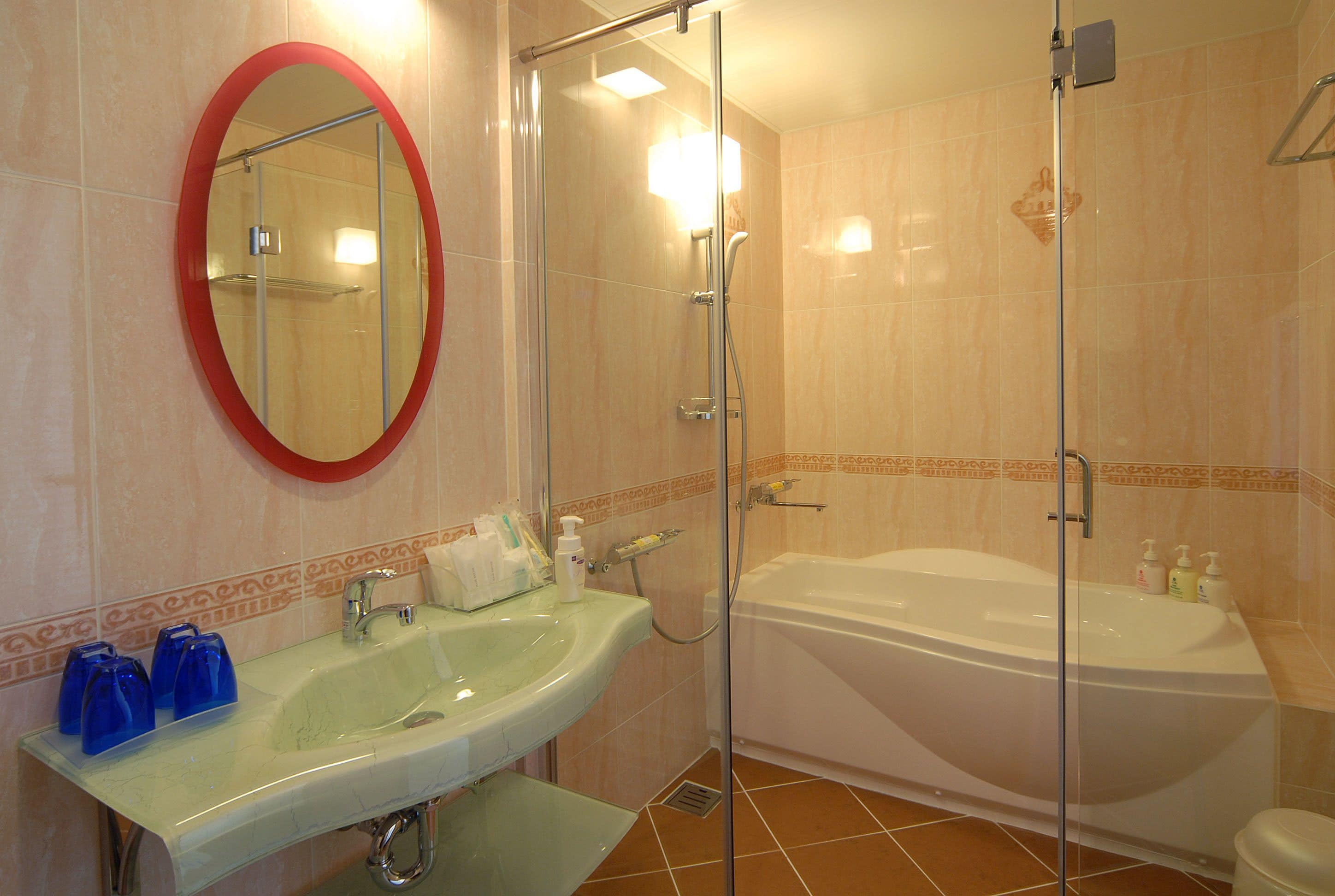 Une salle de bain avec une douche à parois de verre, une baignoire blanche et un lavabo doté de distributeurs de savon bleus.