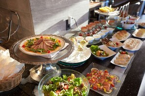 Un bufé con diversos platillos, entre ellos ensaladas, carnes y postres.