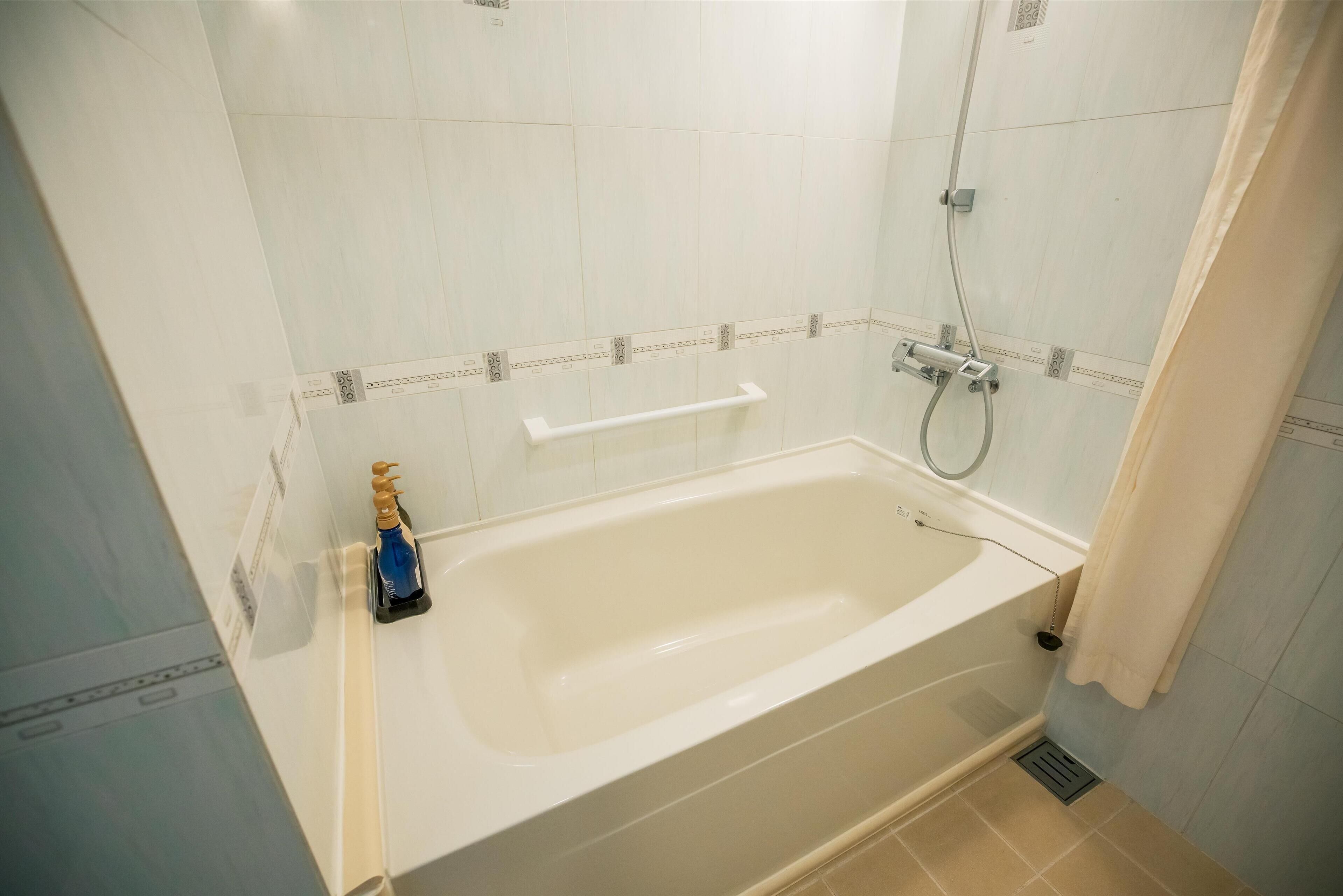 Une salle de bain avec une baignoire, une douche et un porte-serviettes.