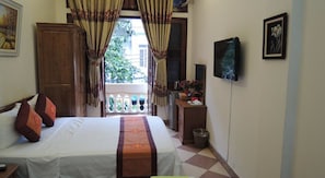 A bedroom with a bed, curtains, a TV, and a balcony with a view.