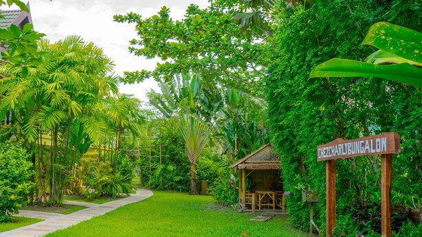 Un jardín exuberante con un letrero de madera que dice 'CHEZCHARLIBUNGALOW'.