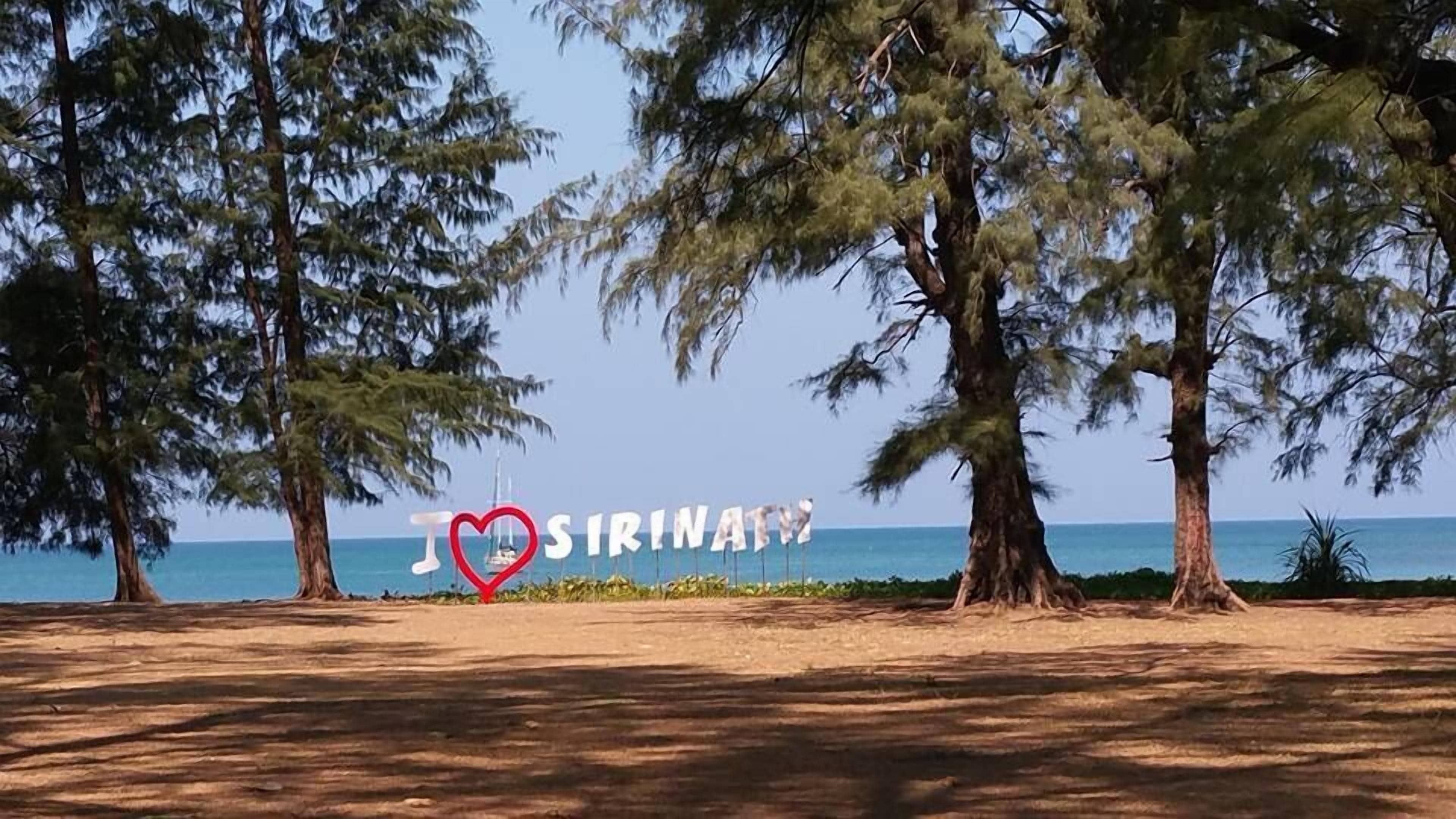 Een strand met bomen en een bord waarop staat 'I ♥ SIRINATW'.