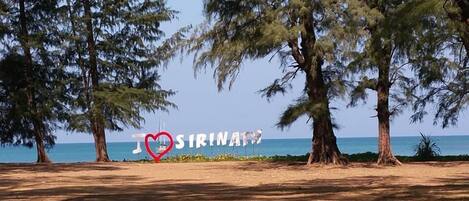 Een strand met bomen en een bord waarop staat 'I ♥ SIRINATW'.