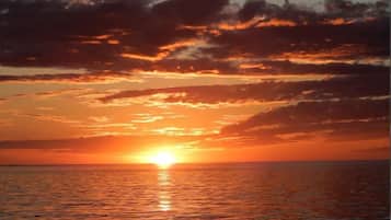 A sunset over the ocean with silhouettes of people in the foreground.