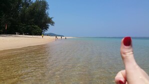 Una playa despejada con gente caminando por la orilla y una vista clara del agua.