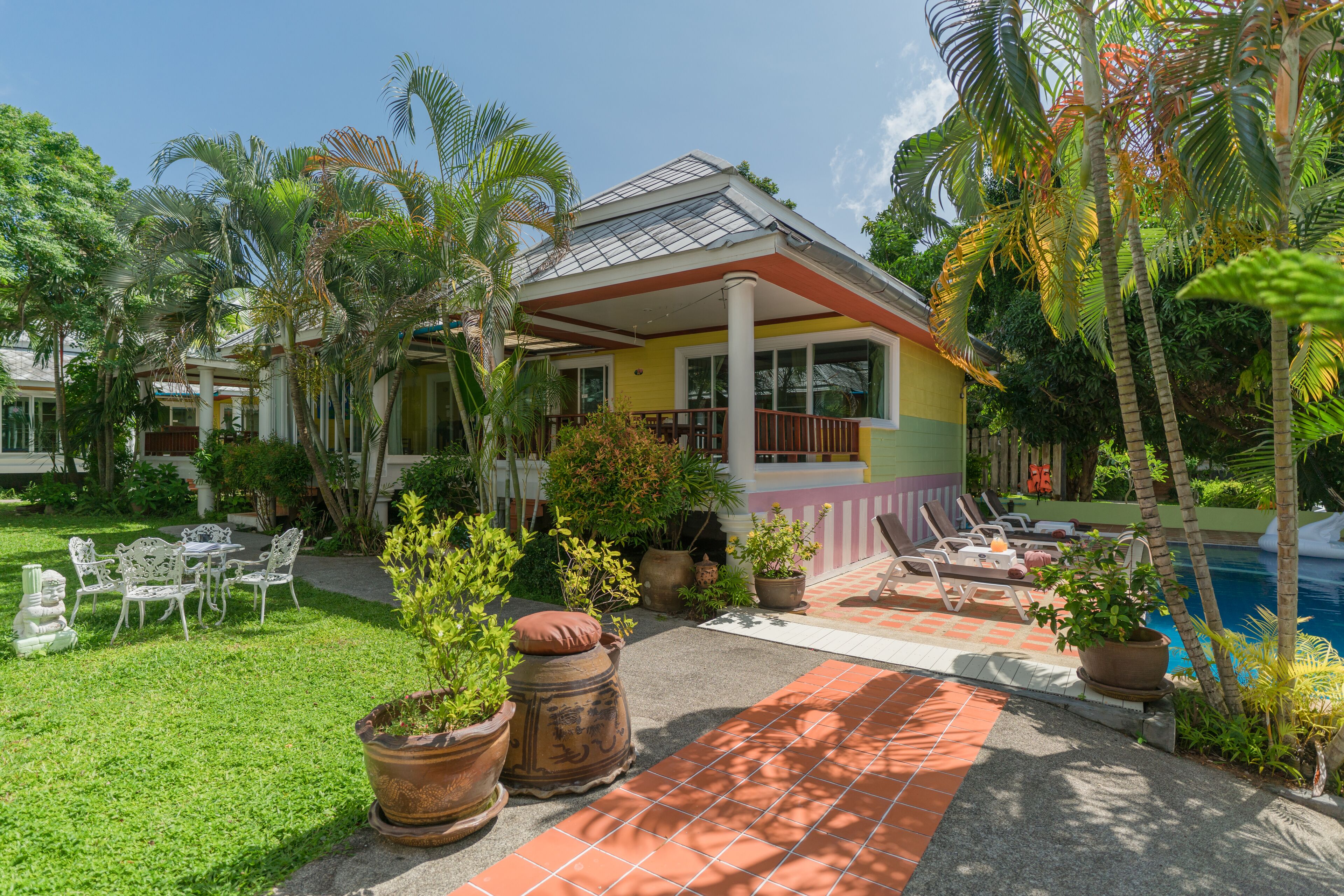 A tropical resort with a pool, outdoor seating, and lush greenery.