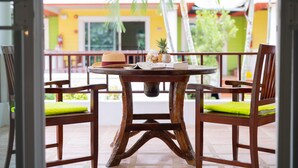 A wooden table with a rustic design, two chairs with green cushions, and a small decorative item on the table. - Lemon House (Patong)