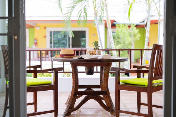 A wooden table with a rustic design, two chairs with green cushions, and a small decorative item on the table.
