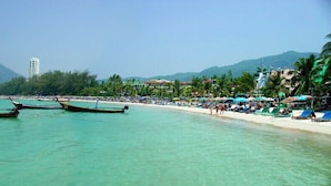 A beach with boats, umbrellas, and people. - Naka Resort (Kamala)
