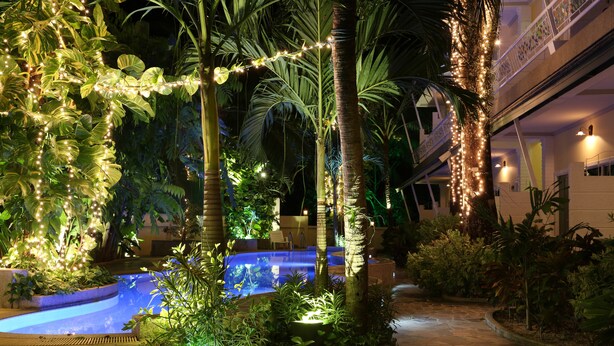 A pool area with surrounding tropical plants and string lights. - Naka Resort (Kamala)