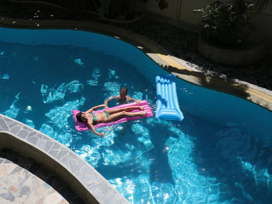 A person floating on a pink float in a swimming pool with clear blue water.