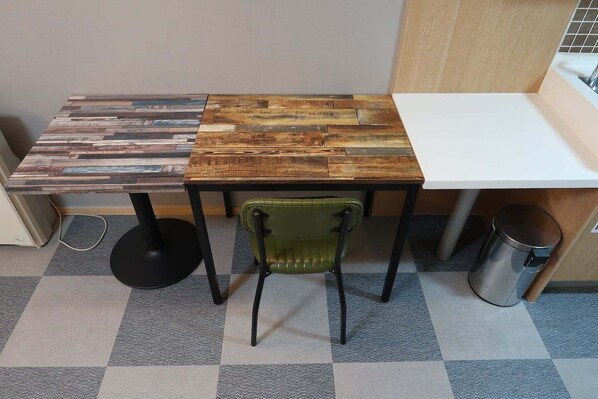 A small, compact workspace with a wooden table and a green chair. - Prime Guest House (Incheon)