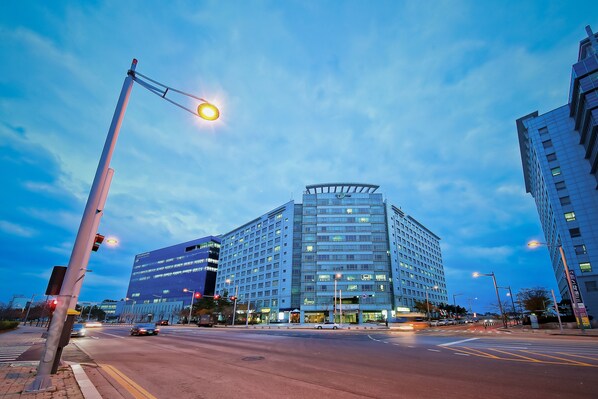 A modern hotel with a prominent corner entrance, multiple floors, and a large glass facade.
