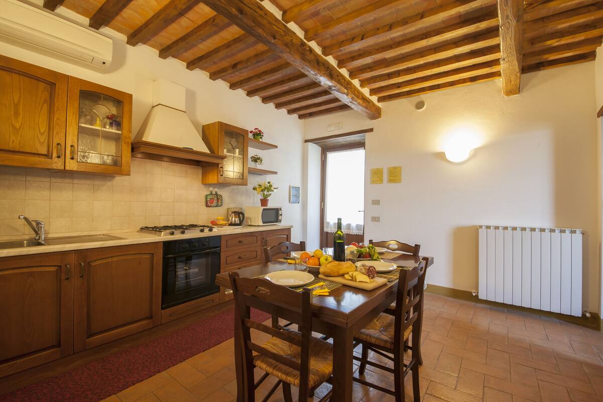 A kitchen with wooden cabinets, a stove, and a dining table set for four.