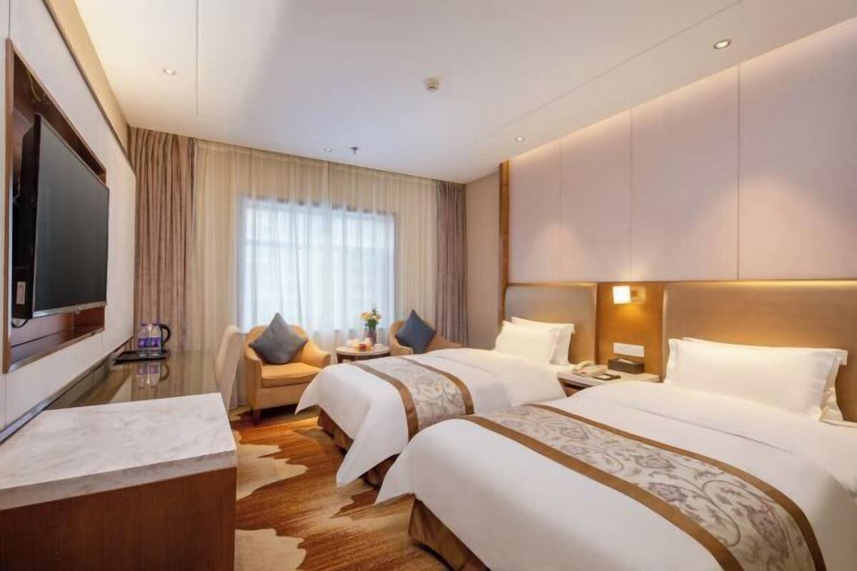 Une chambre d’hôtel avec deux lits, une télévision, un bureau et un canapé.