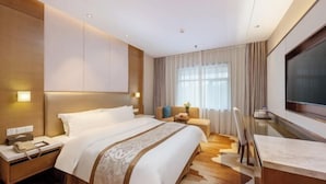 Una habitación de hotel moderna con una cama grande, un escritorio, un televisor y un sofá.