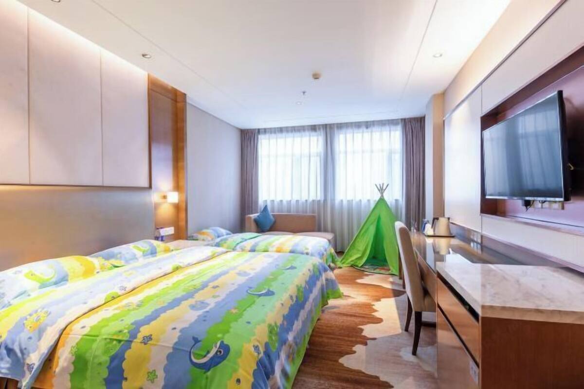 Une chambre d’hôtel avec deux lits, une tente verte, un téléviseur et un bureau.