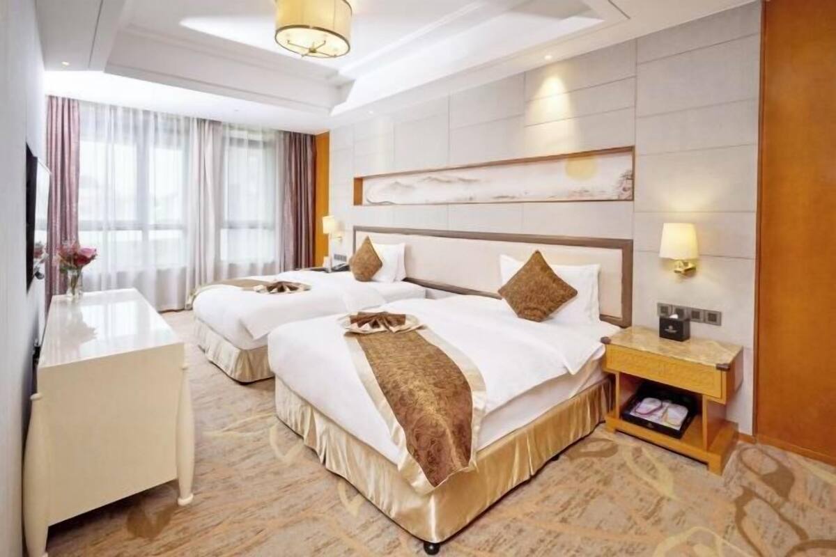 Une chambre d’hôtel avec deux lits, un bureau et une table de chevet.