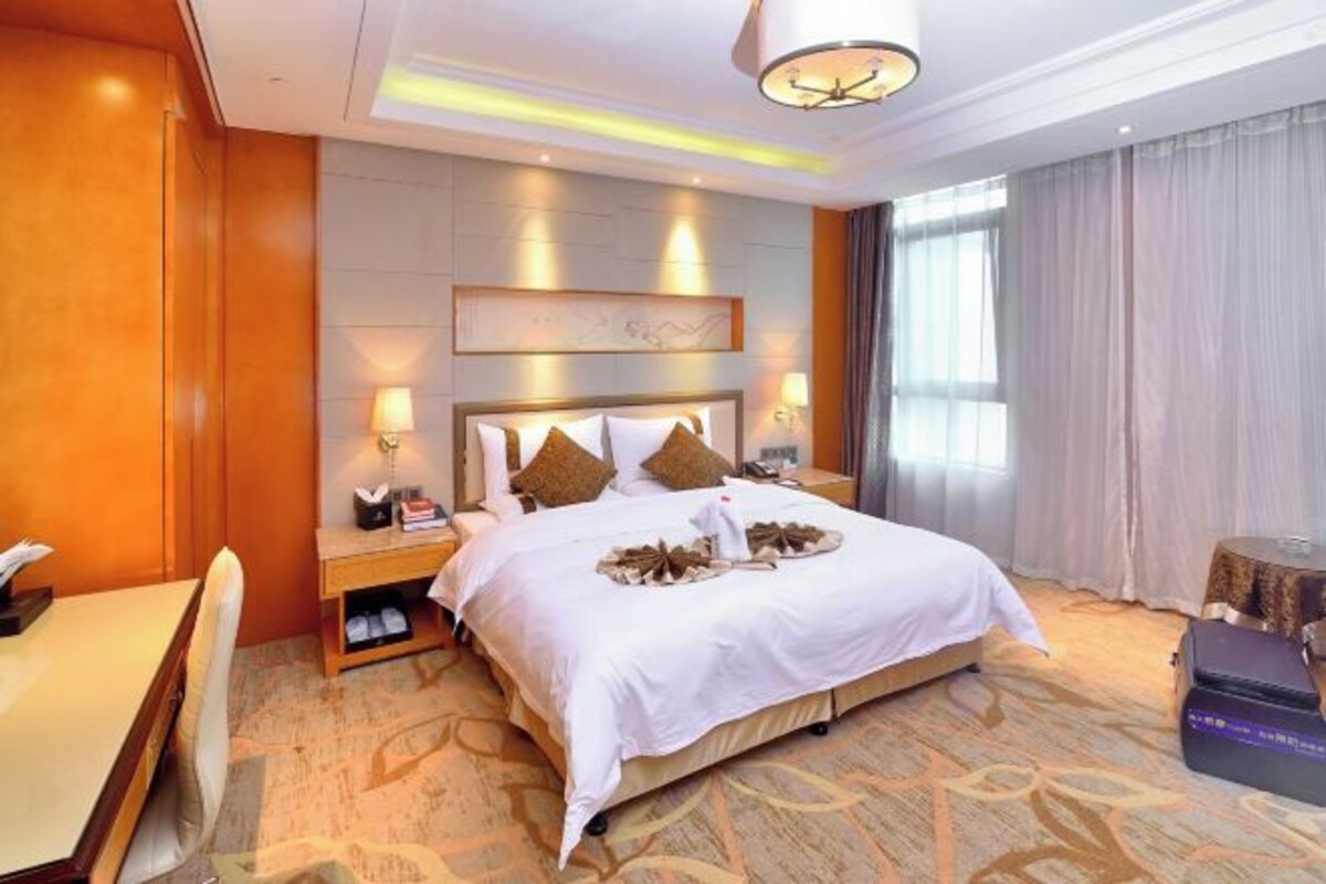 A hotel room with a large bed, bedside tables, a desk, and a chair.