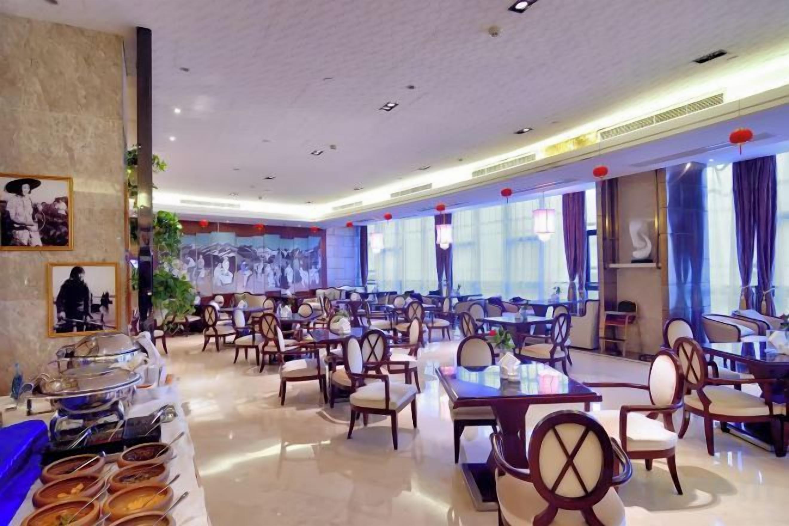 A spacious restaurant with multiple dining tables and chairs, a buffet area, and a mural on the wall.