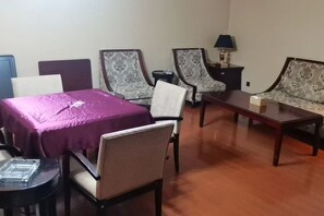 A room with a purple table, two patterned armchairs, a sofa, a small round table, and a lamp on a nightstand. - Mingdu Ziwei Garden Hotel (Changzhou)