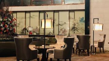 A lobby with a seating area, a decorative wall with artwork, and a floor lamp.