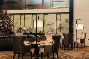 A lobby with a seating area, a decorative wall with artwork, and a floor lamp. - Mingdu Ziwei Garden Hotel (Changzhou)