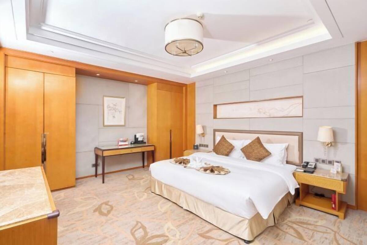 Une chambre d’hôtel avec un grand lit, un bureau et une armoire.