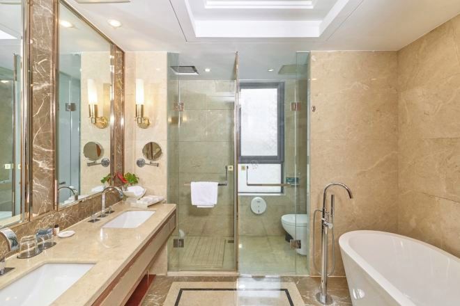 A modern bathroom with two sinks, a glass shower enclosure, a toilet, and a freestanding bathtub.