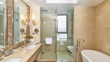 A modern bathroom with two sinks, a glass shower enclosure, a toilet, and a freestanding bathtub.