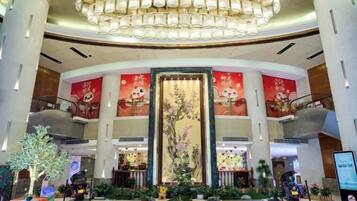 A hotel lobby with a grand chandelier, a large vertical mural, and multiple floors visible.