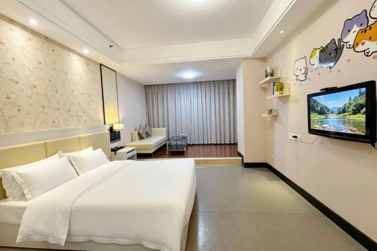 Habitació d'hotel amb un llit gran, una televisió, una taula de treball i una cadira.