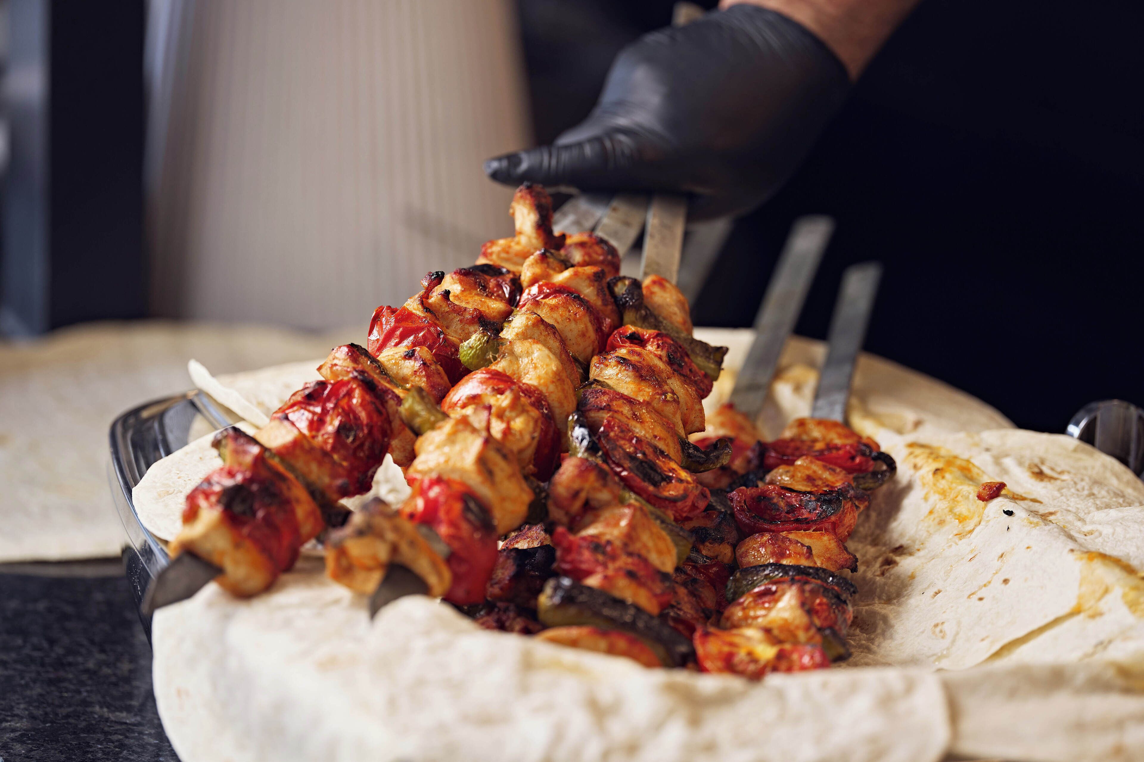 Eine Person grillt Fleisch und Gemüse auf einem Grill.
