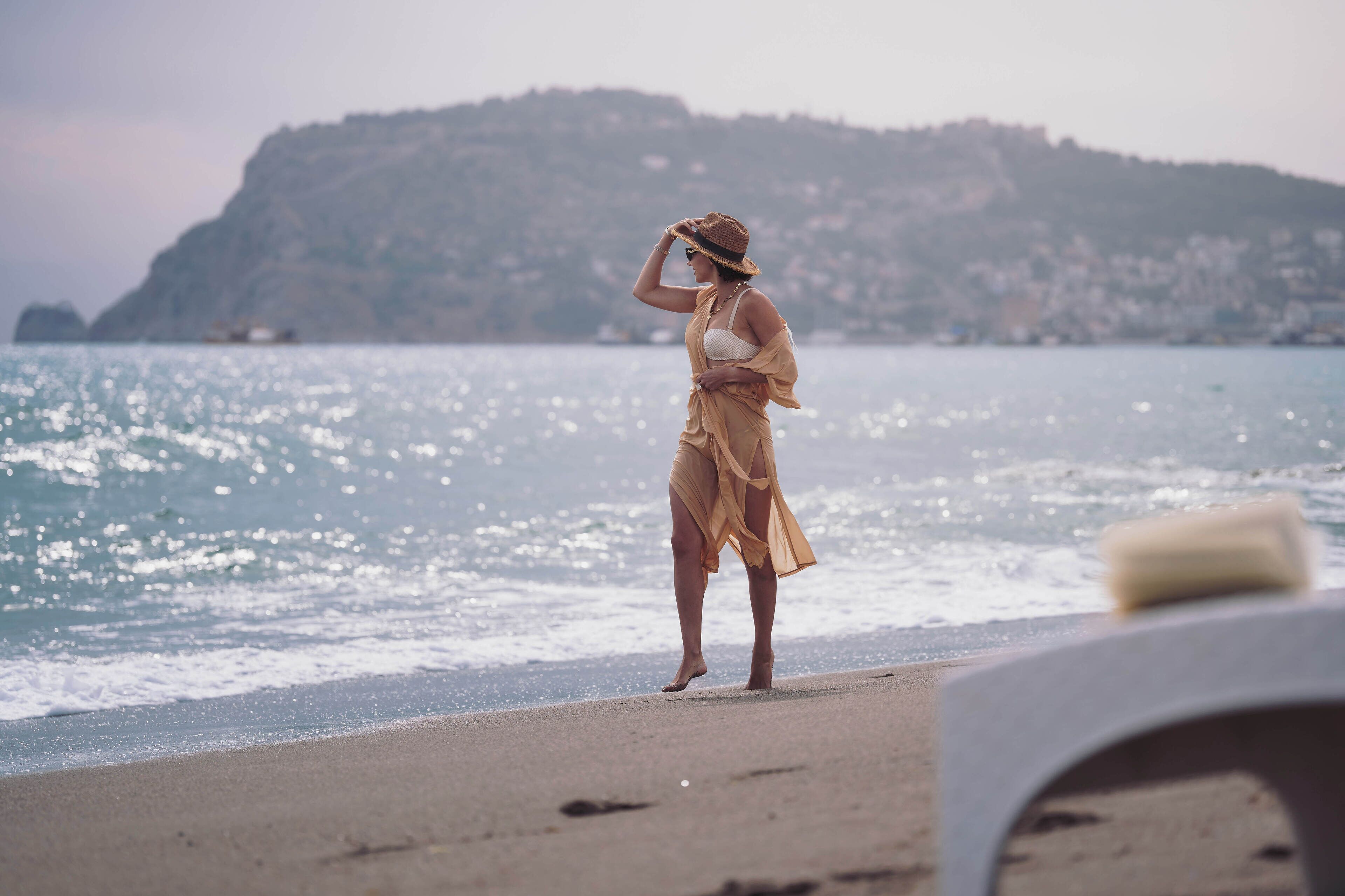 A person standing on a beach with a mountainous background.