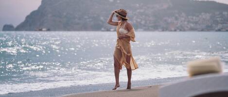 A person standing on a beach with a mountainous background.