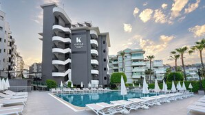 A modern hotel with a swimming pool, white sun loungers, and a clear sky. - Krizantem Hotel - All Inclusive (Alanya)