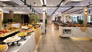 A modern hotel lobby with a long reception desk, multiple seating areas, and a variety of food displays. - Krizantem Hotel - All Inclusive (Alanya)