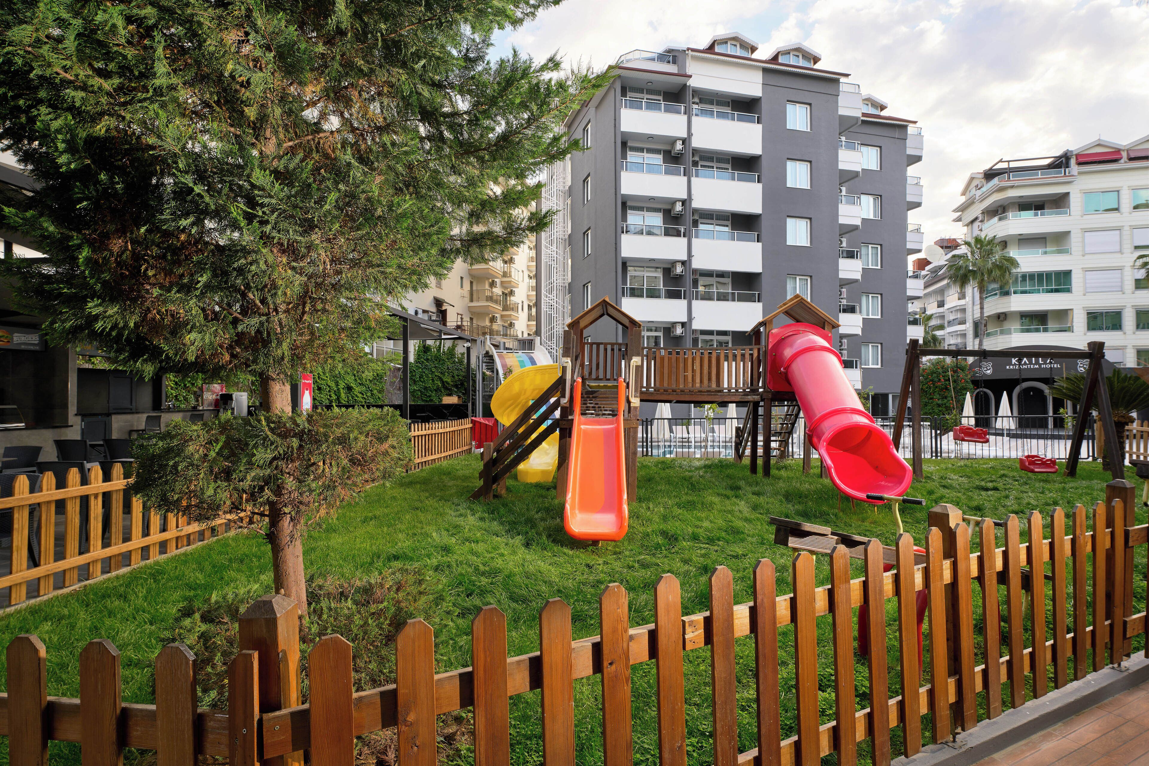 A playground with slides and a wooden fence.
