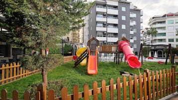 A playground with slides and a wooden fence.
