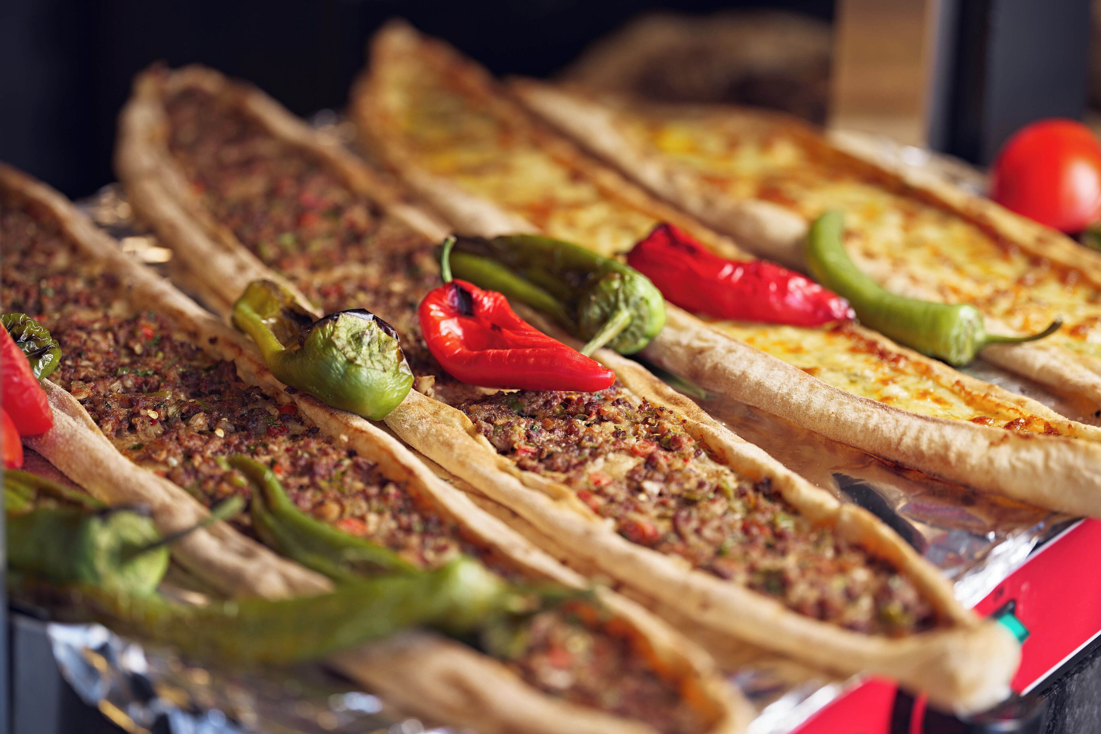 A variety of flatbreads with toppings, including some with red and green peppers.