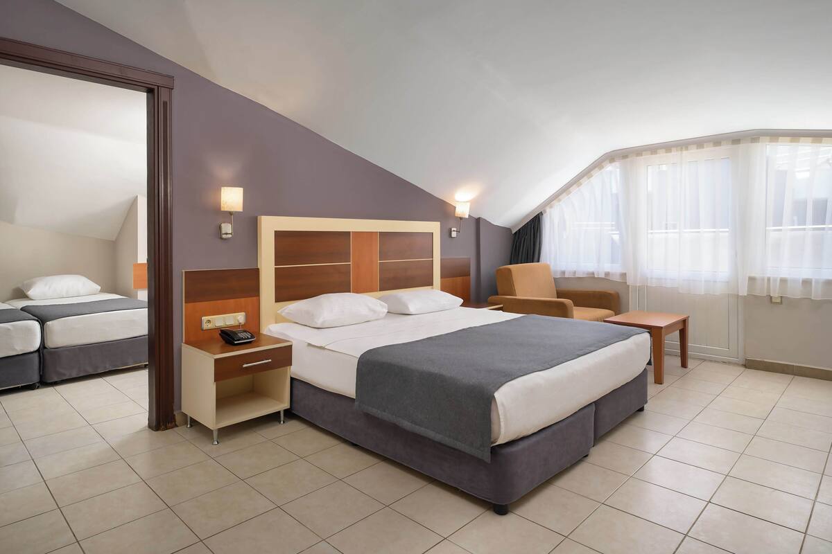 A hotel room with a large bed, bedside tables, a chair, and a desk.