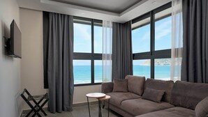 A modern living room with a large sofa, a small round table, and a TV mounted on the wall. - Krizantem Hotel - All Inclusive (Alanya)