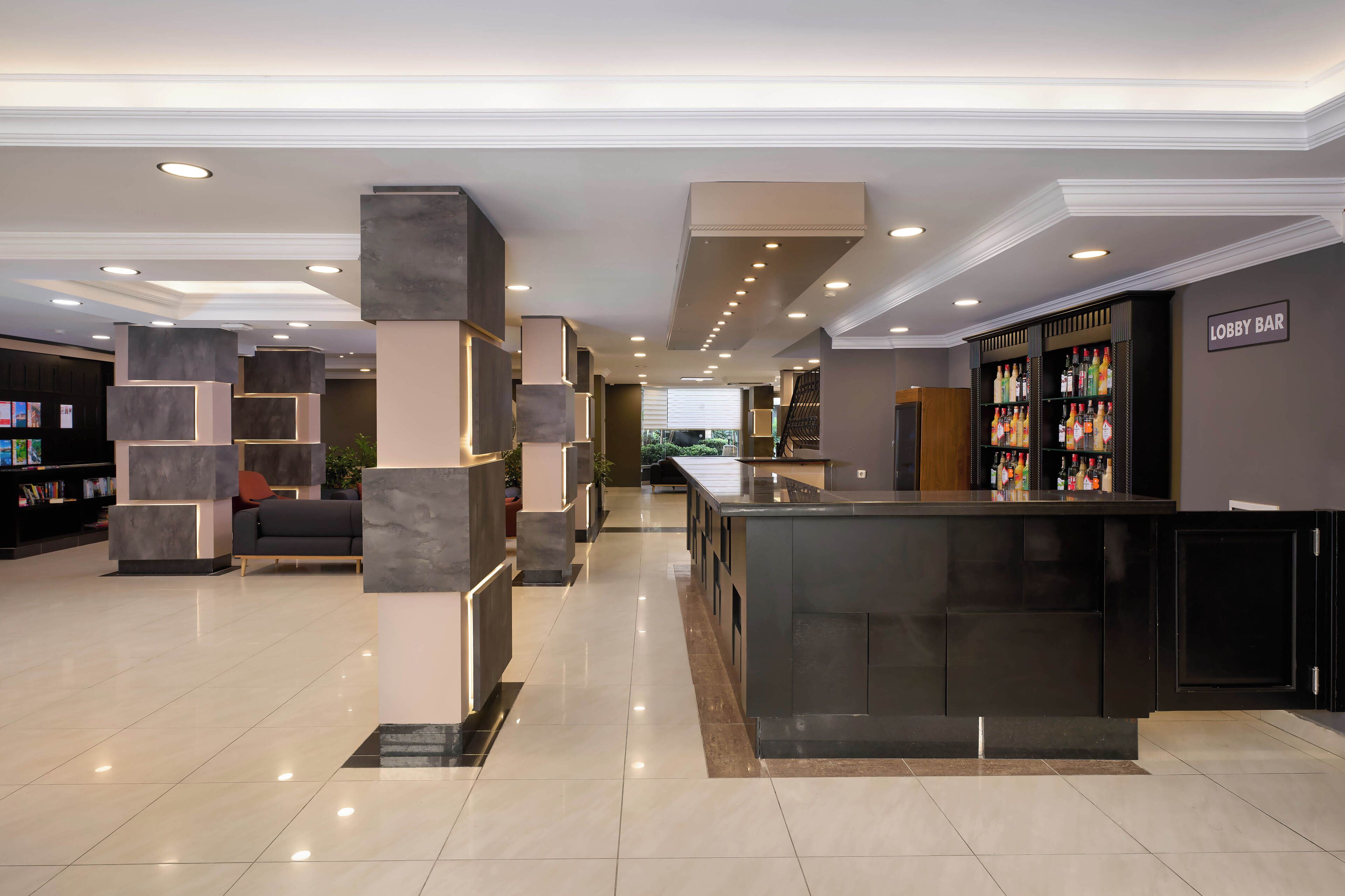 Un vestíbulo moderno con zona de bar, asientos y mostrador de recepción.
