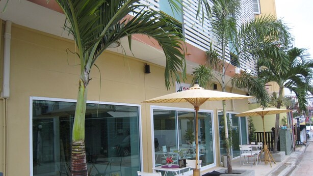 Hotelgevel met terras, palmbomen en grote ramen.