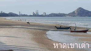 Ein Strand mit Booten und einer fernen Stadtansicht.